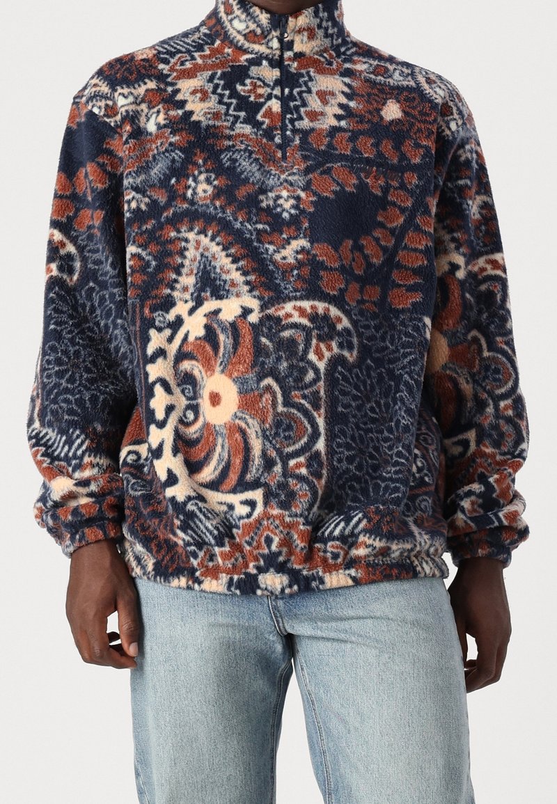 Pullover in pile con mezza cerniera in motivi floreali e geometrici blu, arancione e crema; vestibilità morbida con polsini ed orlo elastici.