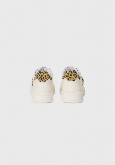 Sneakers bianchi con pannello posteriore in stampa leopardata gialla testurizzata, caratterizzati da punta rotonda e suola spessa color crema. Design minimalista, senza accessori.