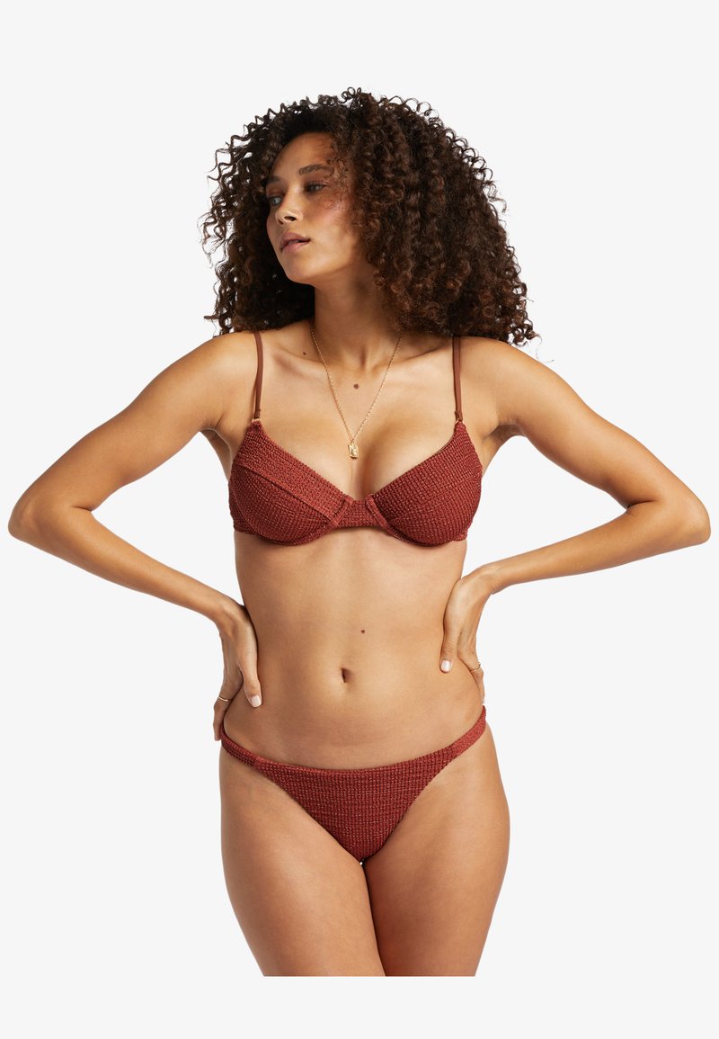 Roter strukturierter Bikini mit einem unterstützenden BH-Oberteil und dünnen verstellbaren Trägern; passende tief geschnittene Unterteile.