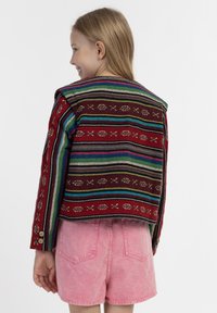 Raudonas raštuotas švarkas su daugybe spalvotų juostelių ir siuvinėtų akcentų. Turi ilgas rankoves ir dekoratyvinius mygtukus ant rankogalių.