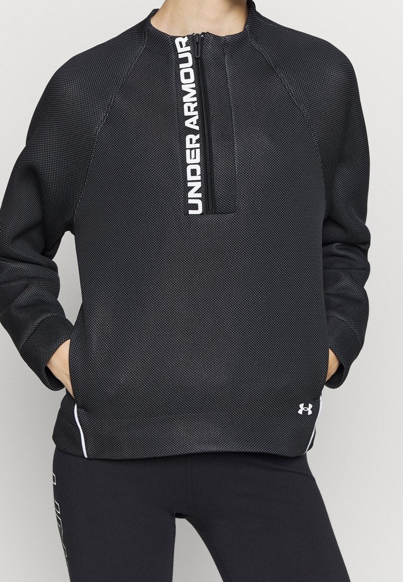 Felpa nera con superficie testurizzata, collo a metà zip e logo "UNDER ARMOUR" bianco. Presenta maniche raglan e dettagli bianchi.
