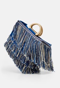 Fransväska med trähandtag i cirkelform; har lager av blå och gräddfärgad fransdetaljering, tygkropp och rektangulär form.