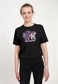 Čern�é bavlněné tričko se barevným logem MTV na kostkovaném pozadí a akcenty v fialové, zelené a bílé.