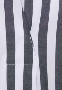 Baumwollstoff mit abwechselnd schwarzen und weißen vertikalen Streifen. Verfügt über eine saubere Naht und eine subtile Textur. Keine zusätzlichen Muster oder Akzente.