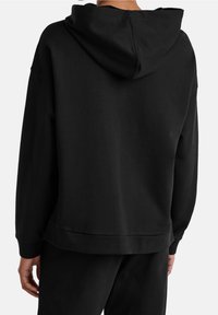 Sudadera con capucha negra de corte relajado y puños acanalados. Textura suave y diseño minimalista sin logos ni patrones visibles.