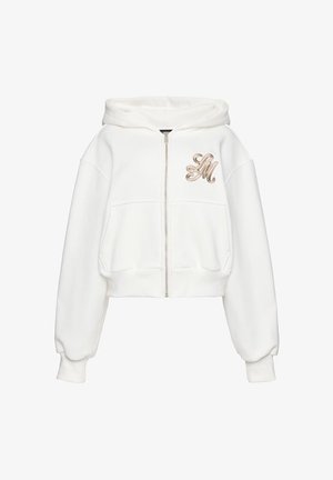 Biały krótki dres z suwakiem, z przodu kieszenie i beżowe haftowane inicjały "LM" na piersi, z kapturem i długimi rękawami.