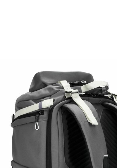 Zaino grigio con schienale imbottito, spallacci regolabili e chiusura superiore. Presenta una cerniera e dettagli bianchi, con pannelli laterali testurizzati.