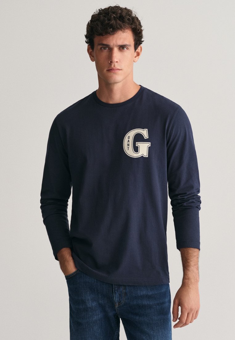 Námořnická košile s dlouhým rukávem z bavlny s bílým logem "GANT G" na levé části hrudi. Střih je volný, vhodný pro každodenní nošení.