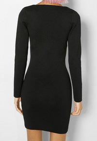 Robe noire moulante à manches longues avec un décolleté carré, en tissu extensible. Texture lisse et longueur au-dessus du genou.