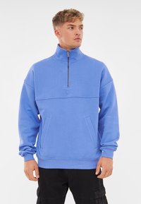 Lichtblauwe, rits-sweatshirt met een hoge kraag, verlaagde schouders, twee voorkliks en ribgebreide manchetten en zoom. Zachte textuur.
