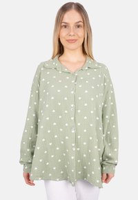 Light green button-up shirt with a textured fabric, featuring white heart patterns and a notched collar. Long sleeves with buttoned cuffs.