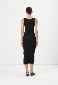 Czarna dopasowana sukienka midi z szerokimi ramiączkami, wykonana z gładkiego materiału, charakteryzująca się klejącą sylwetką i subtelnymi detalami szwów na plecach.