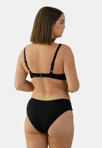 Ensemble de bikini noir avec des détails texturés, des bretelles réglables et une fermeture à crochets au dos. Le bas taille haute complète le design.
