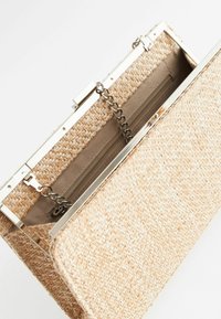 Bolso de mano rectangular de mimbre beige con marco plateado, cadena y bolsillo interior con cremallera sobre un fondo blanco.