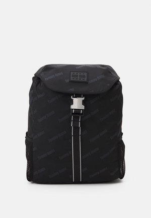 Zaino Tommy Jeans nero con top a pattina, fibbia metallica anteriore, cinghia verticale con cuciture bianche e tasche laterali in rete.