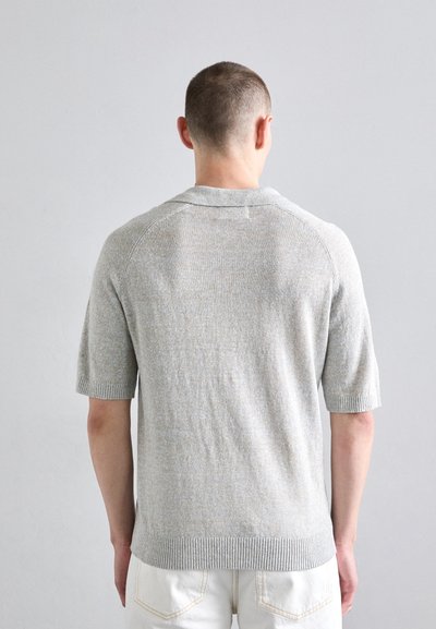 Polo gris à manches courtes avec un ourlet et un col côtelés, en tissu tricoté texturé, présentant une légère variation de couleur et des manches raglan.