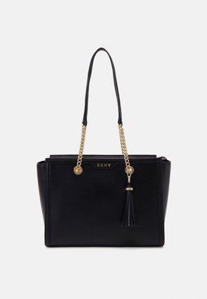 Bolso DKNY de cuero negro con asas de cadena dorada y detalle de borla en la parte frontal sobre fondo blanco.