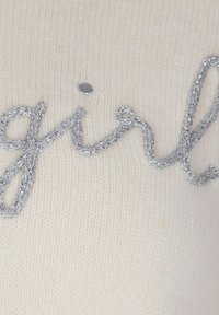 Tessuto a maglia crema con ricamo in argento metallico che scrive "girl", con una finitura liscia e testurizzata e un leggero lucido.