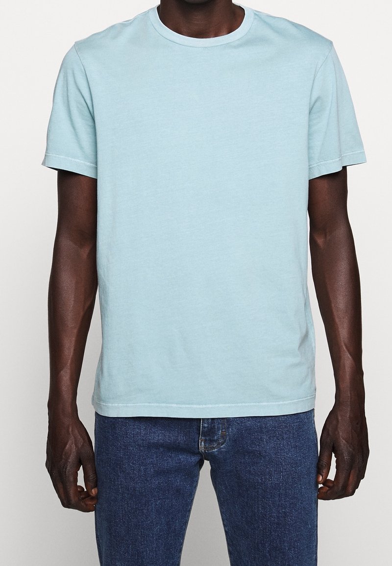 T-shirt en coton bleu clair avec un col rond, des manches courtes et une coupe décontractée. Présente un design simple sans motifs ni accents visibles.