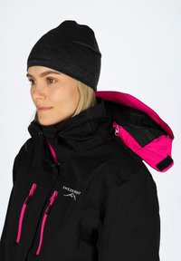 Black jacket with pink accents, featuring a high collar, zippers, and a soft fabric beanie. The inner lining is visible at the collar.