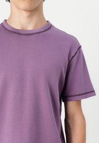 Purple short-sleeve T-shirt with a round neck, featuring contrasting stitching along the collar and sleeves, made of soft cotton material.