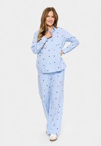 Set di pigiami azzurro chiaro composto da una camicia con bottoni e pantaloni larghi decorati con cuori blu scuro. Tessuto morbido e leggero.