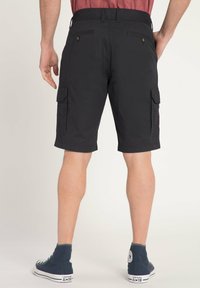 Shorts cargo noirs avec deux poches latérales et une coupe décontractée, dotés d'une taille plate et d'ourlets roulés, associés à des chaussures montantes bleu marine.