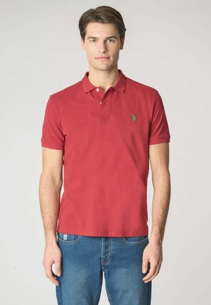 Polo shirt rossa con maniche corte, patta con due bottoni e un piccolo logo verde sul petto. Abbinatela a jeans blu per un look casual.