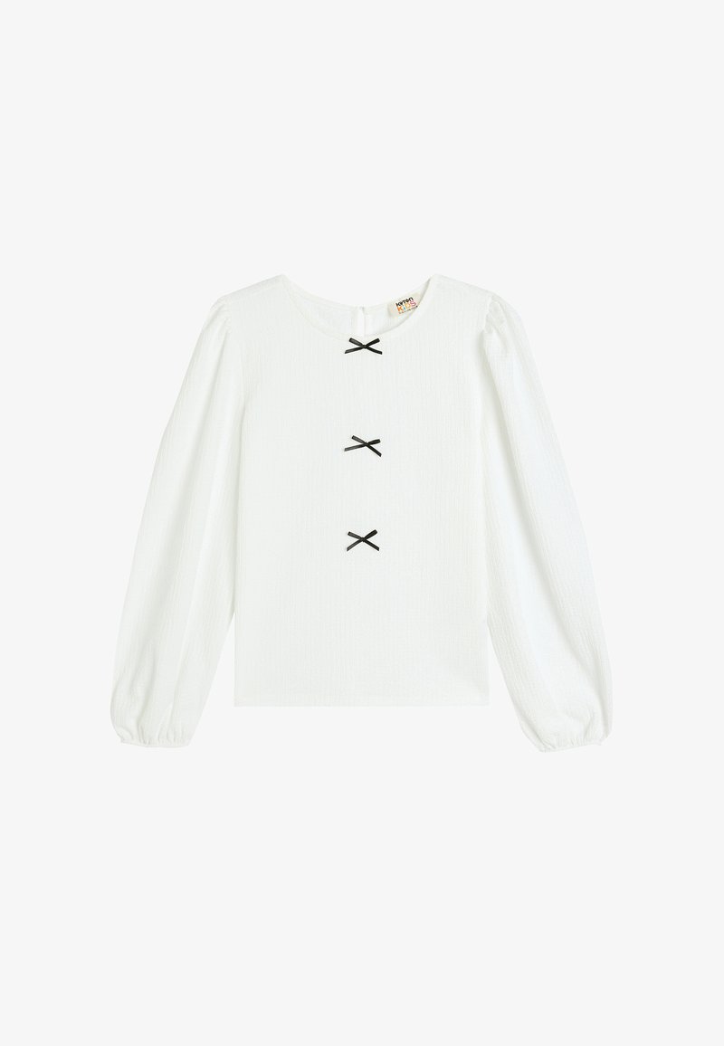 Valkoinen pitkähiha blouse pyöreällä kaula-aukolla, jossa on kolme mustaa rusettiakenttia keskellä ja teksturoitu kangas puffattuin hihoin.