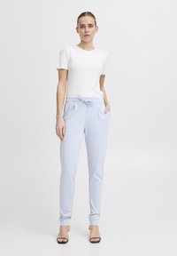 Ribbade vita t-shirts med kort ärm som matchas med ljusblå tapered joggerbyxor med elastisk midja och sidofickor.