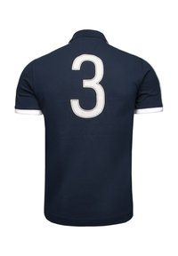 Námořnický polo tričko s bílým límečkem a náplety; na zadní straně se nachází velké bílé číslo 3, vyrobené z měkké, prodyšné bavlny.