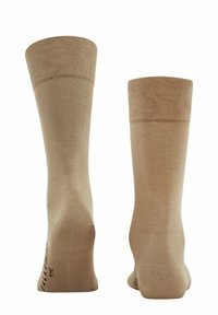 Beige knee-high socks made from a smooth, elastic material. Ribbed tops and subtle patterns near the soles. Straight, even shape.