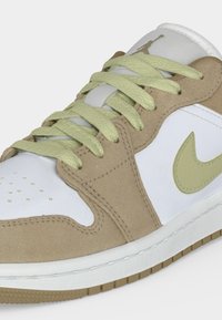 Παπούτσι τύπου sneaker χαμηλού προφίλ με μπεζ σουέντ επενδύσεις, λευκά δερμάτινα πάνελ, ανοιχτό πράσινα κορδόνια και αντίστοιχο λογότυπο Nike στο πλάι.