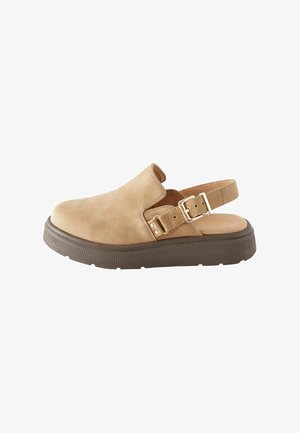 Chaussure slingback en cuir tan avec un bout fermé, boucle ajustable sur le côté, et une semelle plateforme texturée marron.