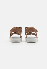 Sandalias de cuero marrón con dos correas ajustables, suelas de goma blanca y una plantilla texturizada y acolchada para mayor comodidad.