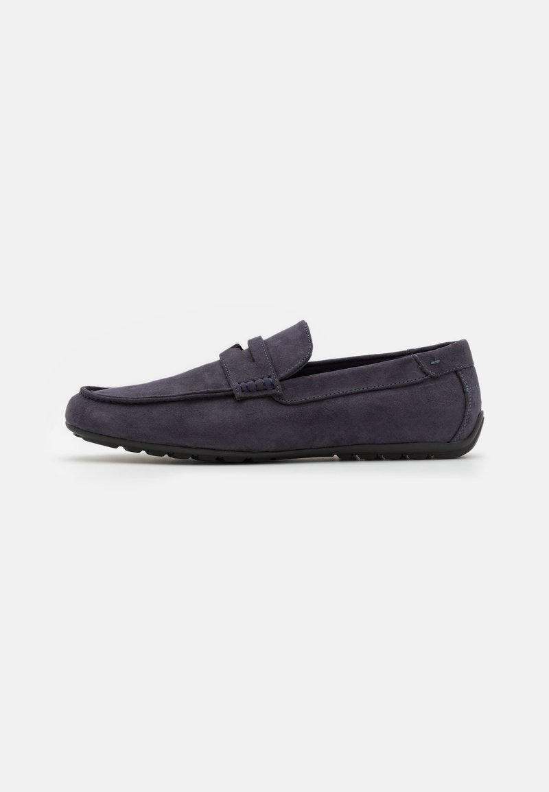 Mocassin en daim gris foncé avec un petit talon, un bout arrondi et une bride sur le dessus, présenté de profil sur fond blanc.