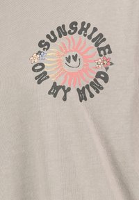 Graues Baumwoll-T-Shirt mit einem bunten Sonnenmotiv mit einem lächelnden Gesicht, das von Blumen umgeben ist, sowie dem Text "SONNENSCHIEN IN MEINEM KOPF" in fetter Schrift.