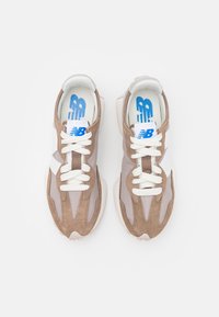 Bruna och grå mockaskor med meshpaneler, vita snören och blå logofunktioner. Rundad tå och dämpad sula.