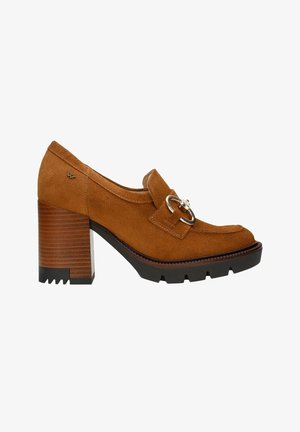 Mocassins à talons en cuir suédé marron avec un détail en boucle, une semelle intermédiaire texturée et une semelle en caoutchouc noir épaisse. Comprend un bout arrondi et des accents surpiqués.