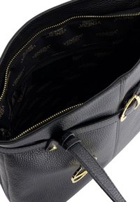Sac à main noir en cuir avec une texture grainée, accents en métal doré et fermeture éclair, comprenant un intérieur en tissu avec logo.