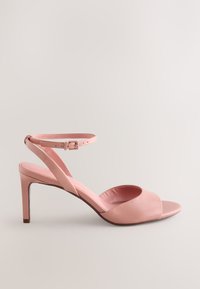 Sandale à talon en cuir rose avec bout ouvert, fine bride à la cheville et talon aiguille de 10 cm. Texture lisse et détails de design minimalistes.