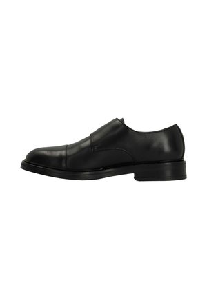 Black leather slip-on shoe featuring a rounded toe, smooth texture, minimalistic design, and a low stacked heel. No visible hardware or embellishments.