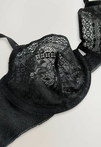 Soutien-gorge en dentelle noire avec motifs floraux, bonnets à armatures et bretelles ajustables, doté d'une base en tissu lisse pour le confort et le soutien.
