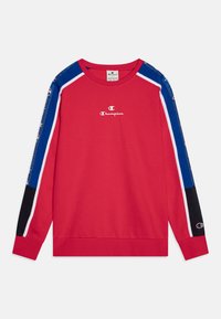 Sudadera de algodón roja con detalles en azul y negro, con rayas blancas en las mangas. Logo impreso en la parte frontal. Corte regular con puños de canalé.