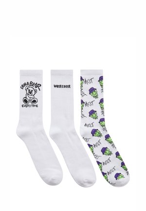 Tre paia di calze: bianche con orsetto grafico nero, bianche con "west coast" e calze colorate con facce verdi che indossano cappelli viola.