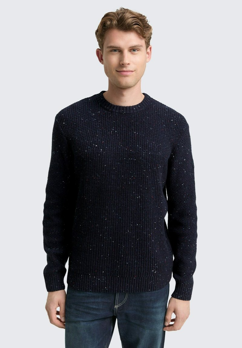 Marineblauer Strickpullover mit gerippter Textur, versehen mit mehrfarbigen Punkten. Klassischer Rundhalsausschnitt und lange Ärmel.