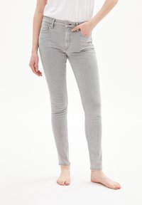 Jeans gris ajustados hechos de denim, con un diseño clásico de cinco bolsillos y una cremallera con cierre de botón. Textura suave.