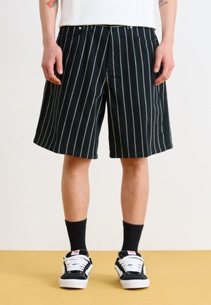 Black striped shorts feature a relaxed fit with a straight leg, made of cotton fabric with a smooth texture. Small pockets are visible.