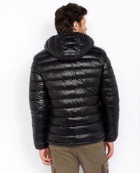 Zwarte pufferjack met een afneembare capuchon, voorzien van horizontale vulling, een gladde textuur en elastische manchetten. Draagt over kaki broeken.