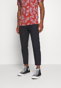 Red short-sleeve shirt with white floral pattern, paired with dark fitted pants and black high-top sneakers with white soles.